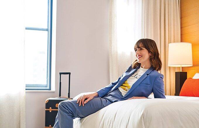 happy professional women sitting on hotel bedding