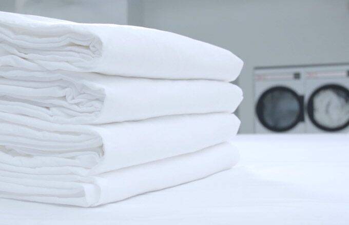 stack of clean white towels on a table in front of washer