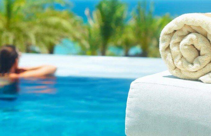 a hotel guest relaxing in a swimming pool with palm trees in the background.