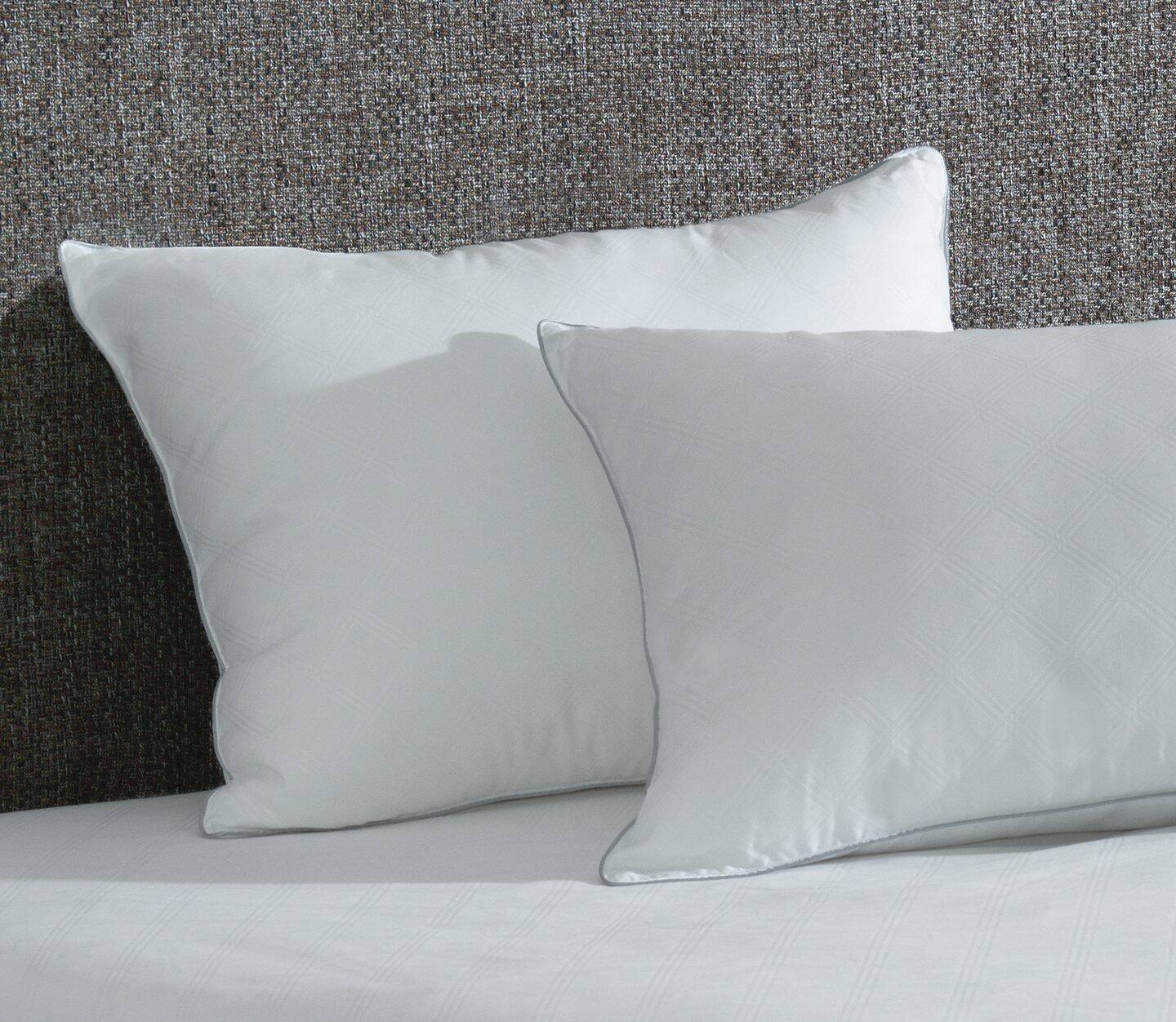 Two AllerEase pillows shown on a bed. These antimicrobial pillows also have a temperature balancing, soft top layer.