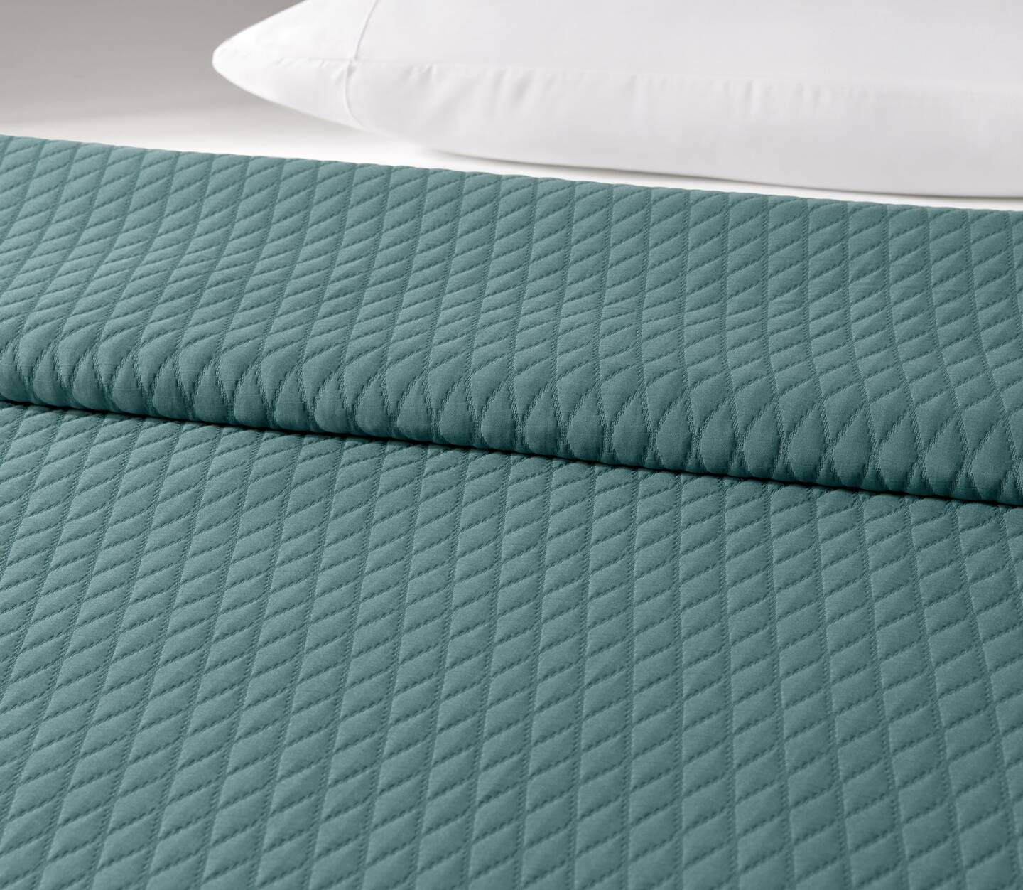 The Keaton bedspread in Storm is shown on a bed.
