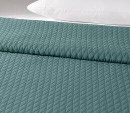 The Keaton bedspread in Storm is shown on a bed.