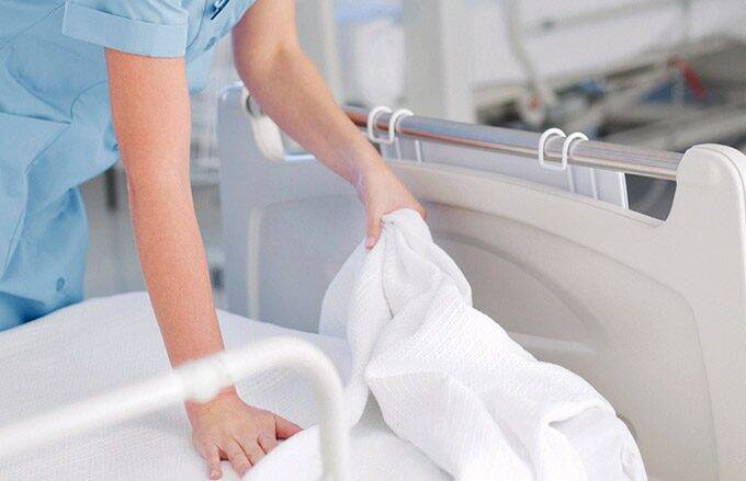 nurse removing hospital bed linens