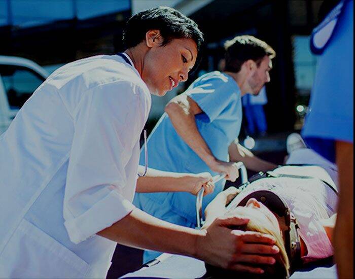 An African American female doctor is triaging a patient on a stretcher. A male nurse is steering the stretcher.