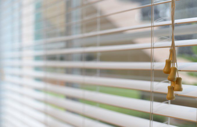 Outdated window blinds with exposed cords in need of replacement.